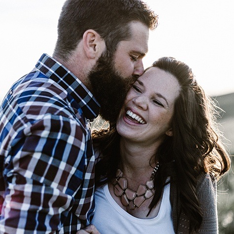 Woman laughing with man kissing her cheek