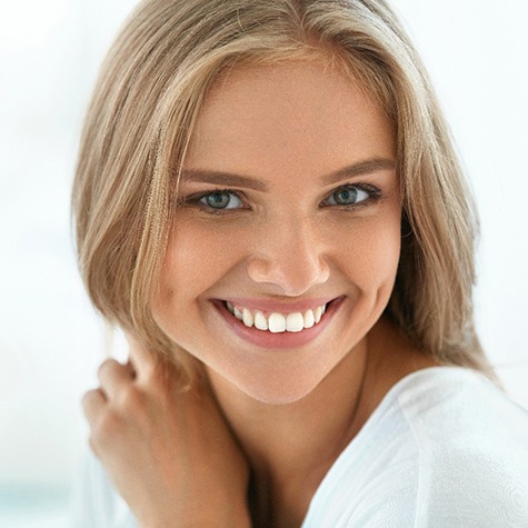 A young woman with blonde hair smiling to show off her new and improved smile