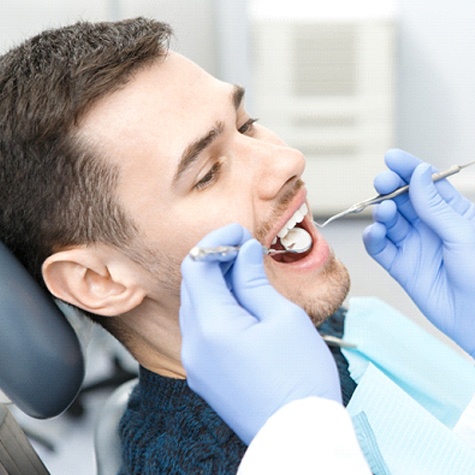 A young man has his teeth checked by his dentist during a regular checkup