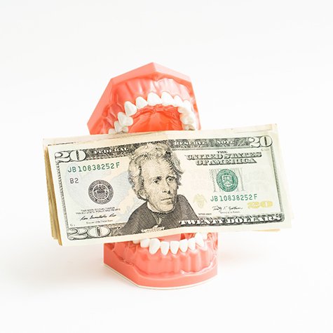 Dentures holding money on white background