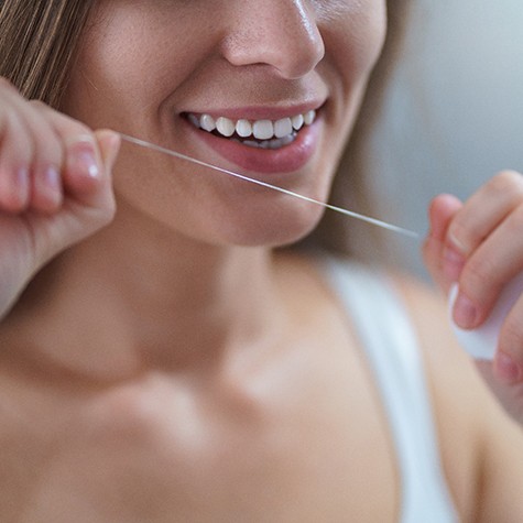Woman flossing to care for dental implants in Doylestown
