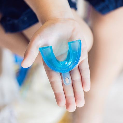 Outstretched hand holding mouthguard for dental implants in Doylestown
