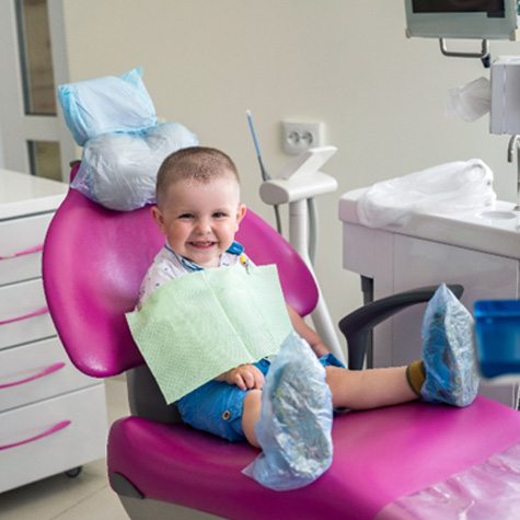 baby smiling while sitting in dental chair  