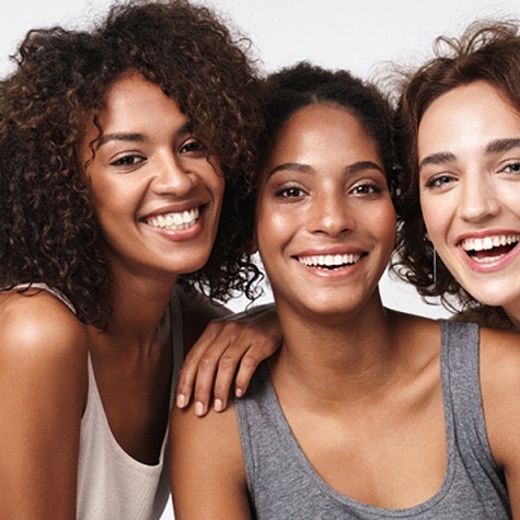 A group of three women all wearing tank tops and showing off their new and improved smiles