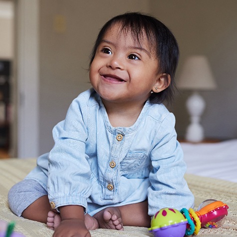 a baby smiling and playing with toys on a bed